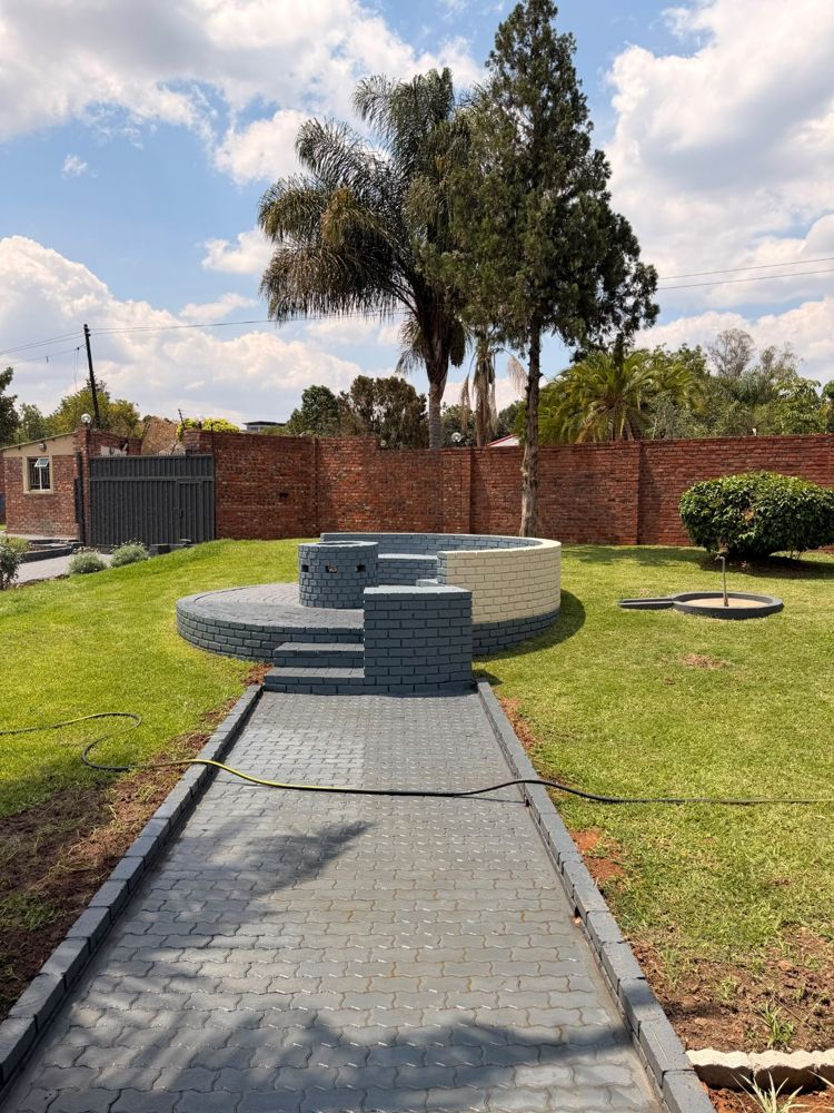 Paved path leading to a round fire-pit seating area on the lawn