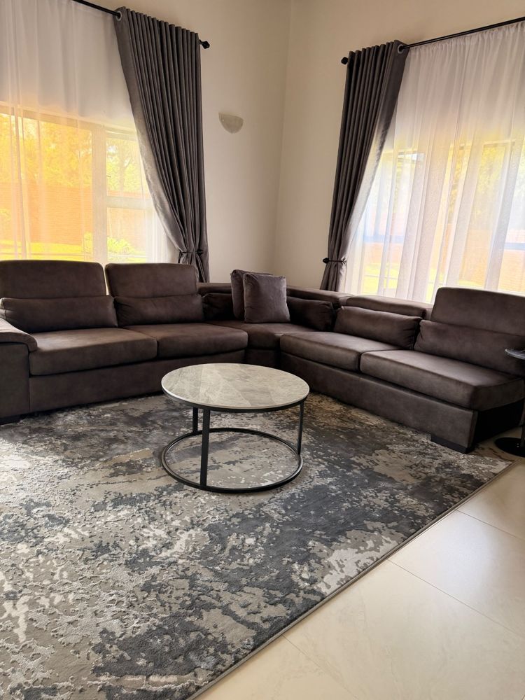 Lounge with large corner sofa, round marble table and grey rug